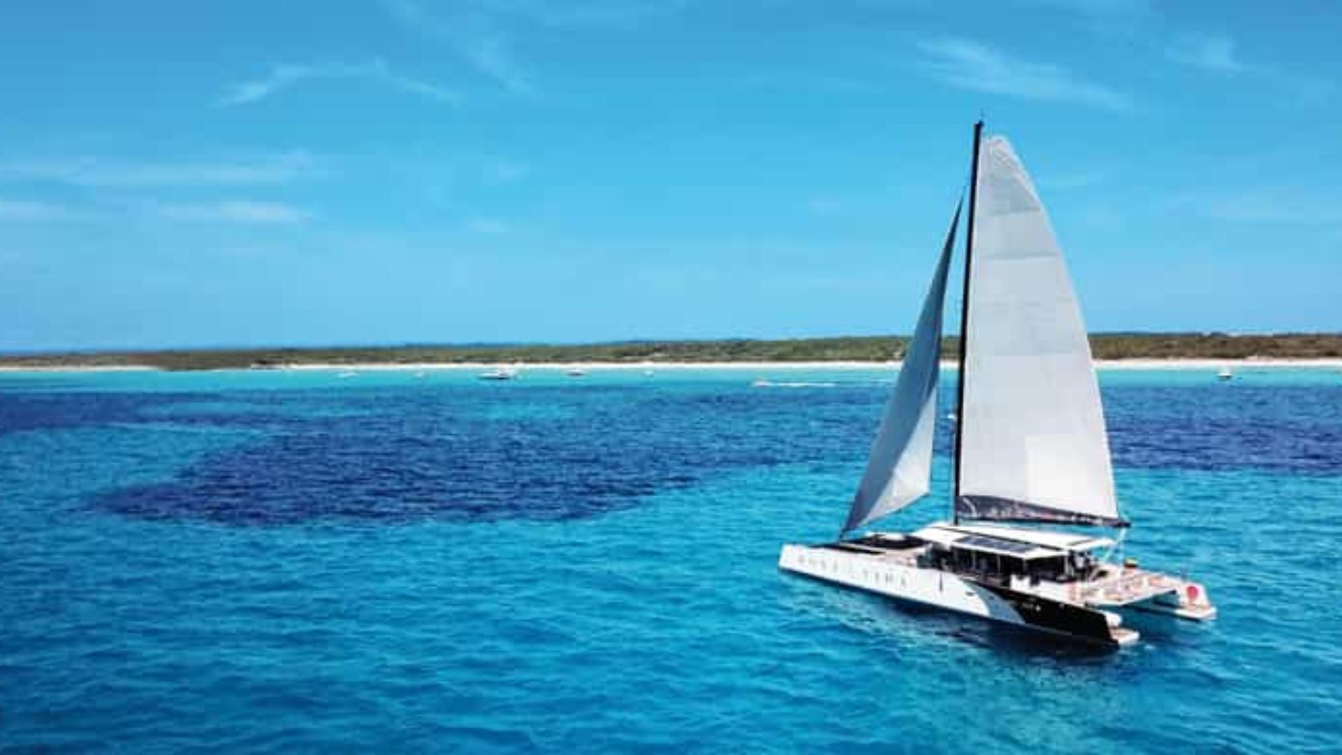 A catamaran sailing on the ocean waves, surrounded by a vast expanse of water.