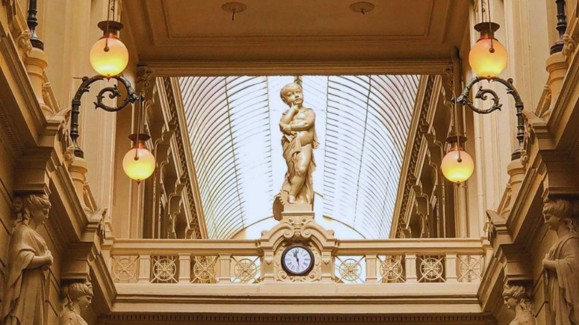 The interior of a building with a prominent clock and various statues displayed throughout.