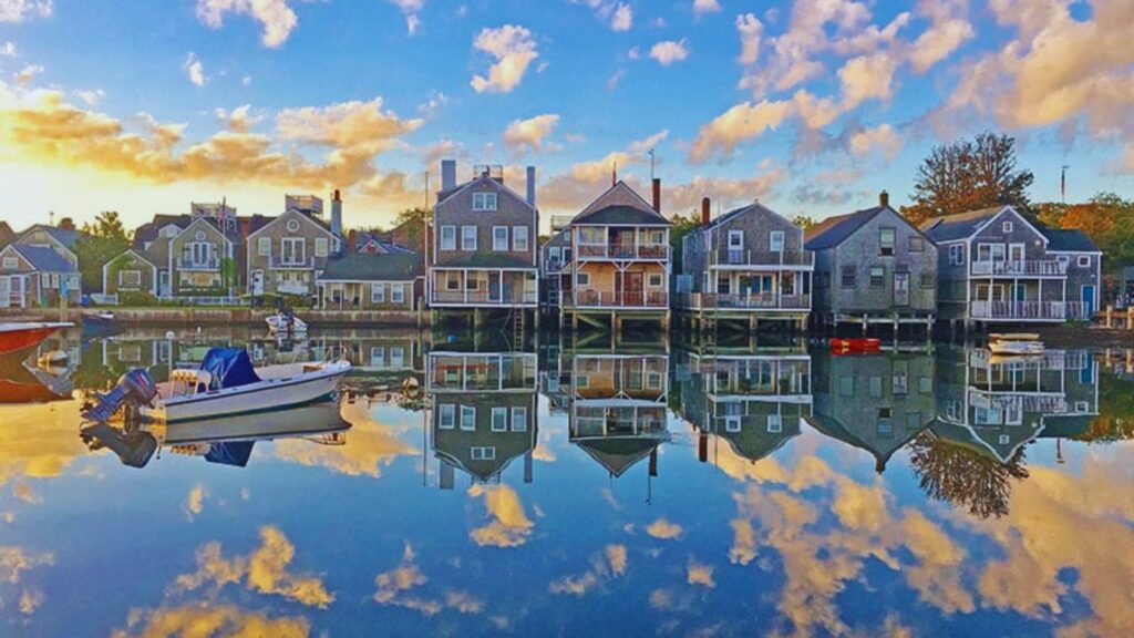 29 Ideas of What to Do in Nantucket for an Amazing Trip A stunning sunset casts vibrant colors over a harbor filled with boats and charming houses along the shoreline.