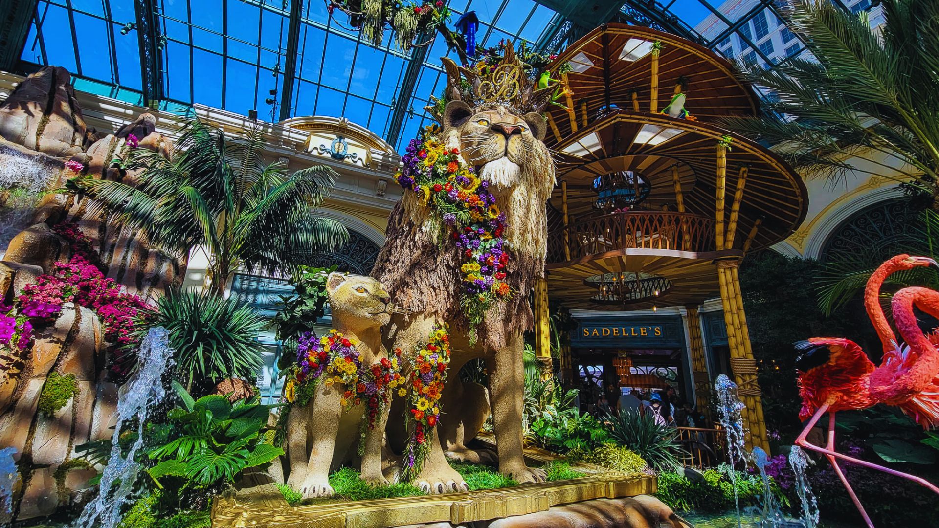 A large statue of a lion and a giraffe stands prominently in a lush garden setting.