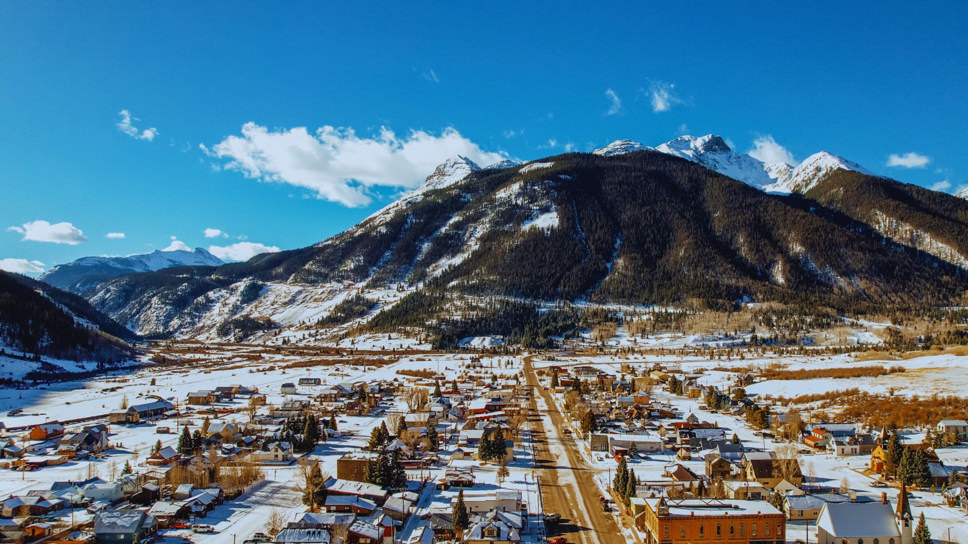 A picturesque town nestled among snow-covered mountains, surrounded by a serene winter landscape.
