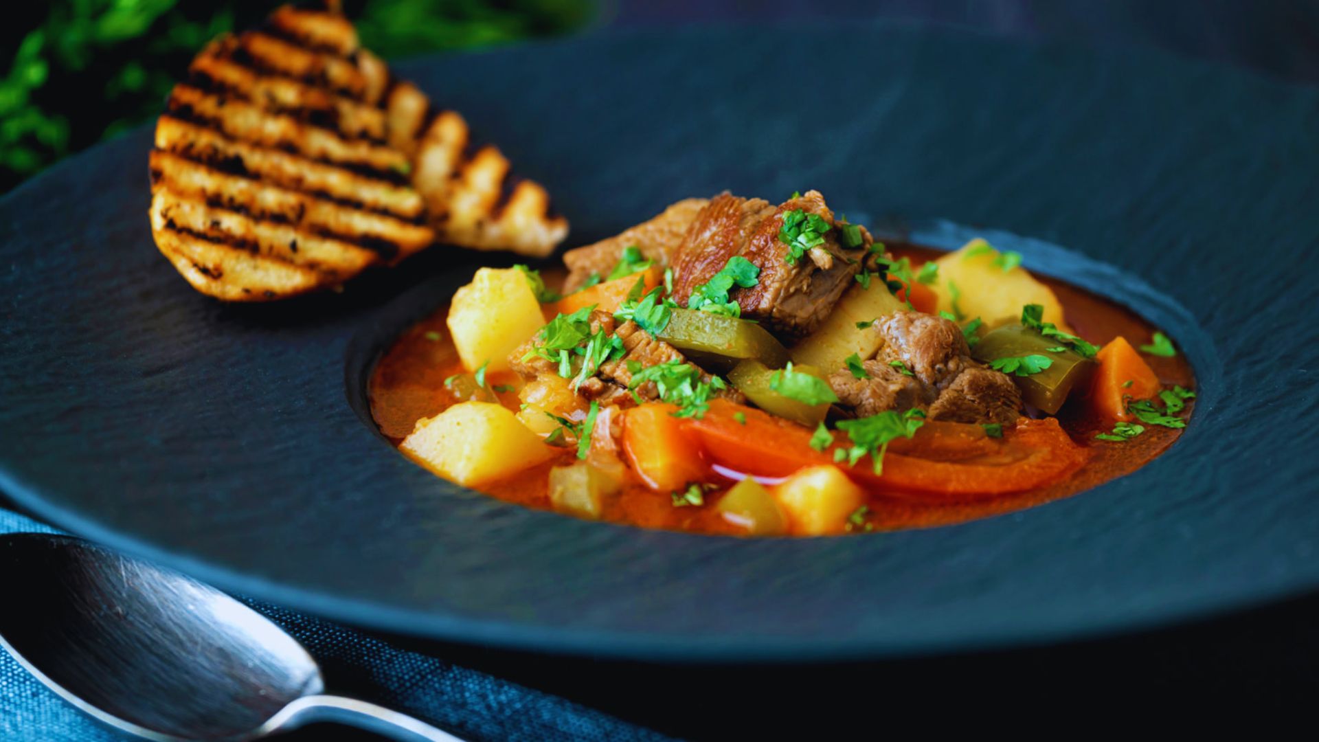 A plate featuring a hearty stew accompanied by a slice of bread, ready to be served.