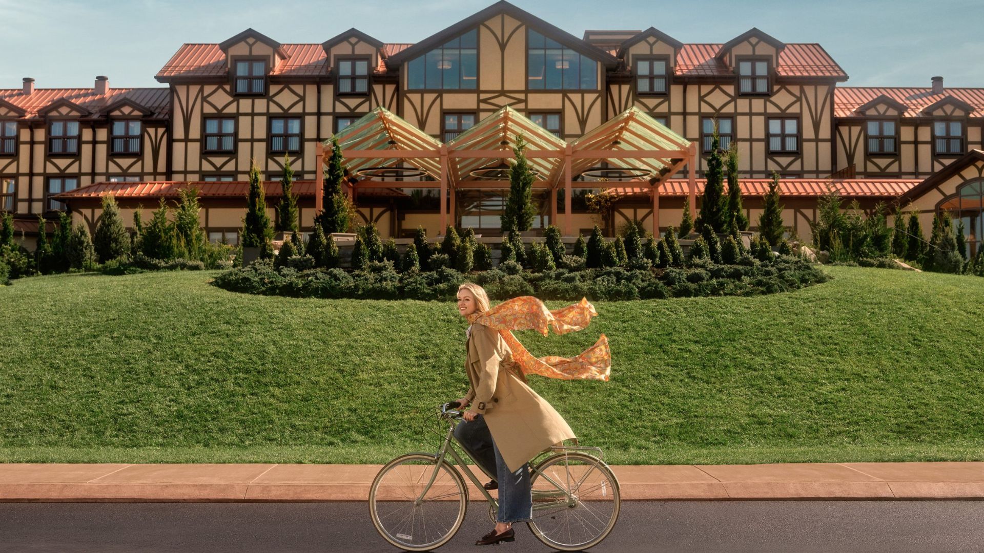 A woman riding a bike in front of a large hotel, showcasing urban life and leisure activities.