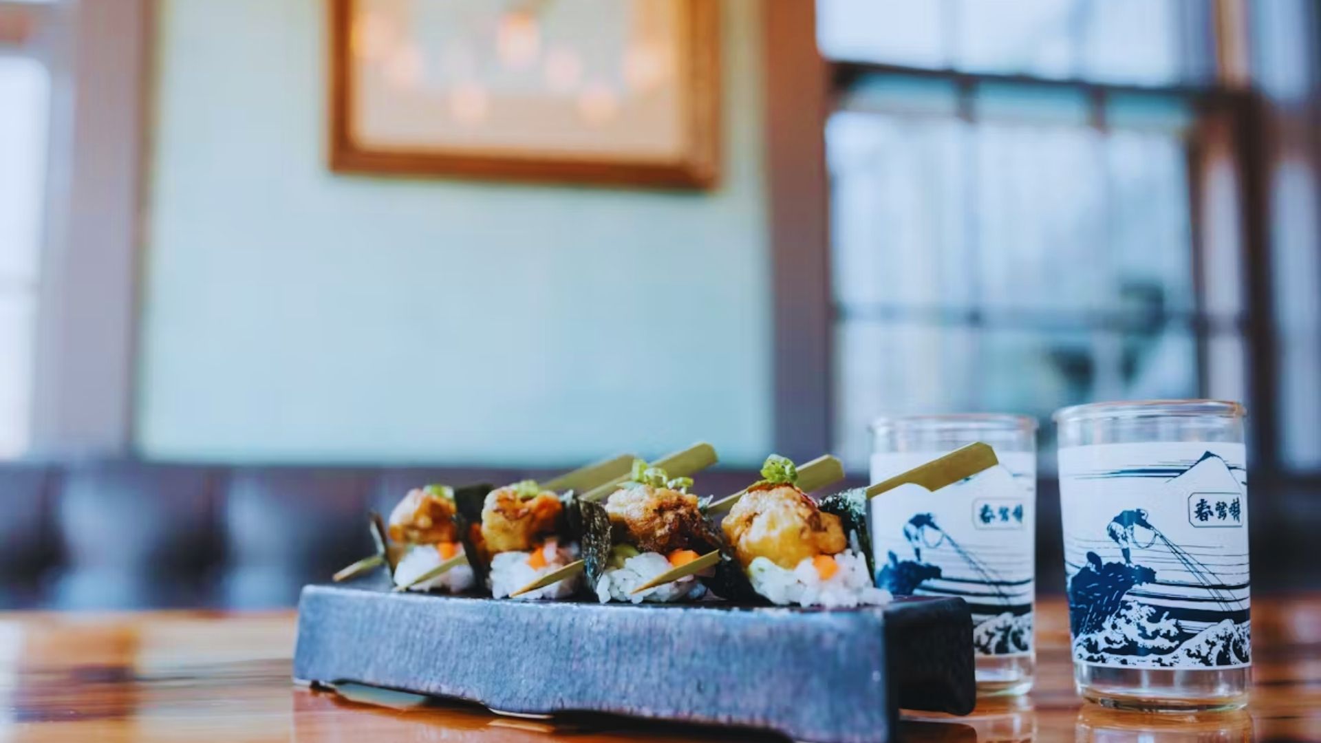 A colorful sushi platter accompanied by drinks, elegantly arranged on a rustic wooden table.