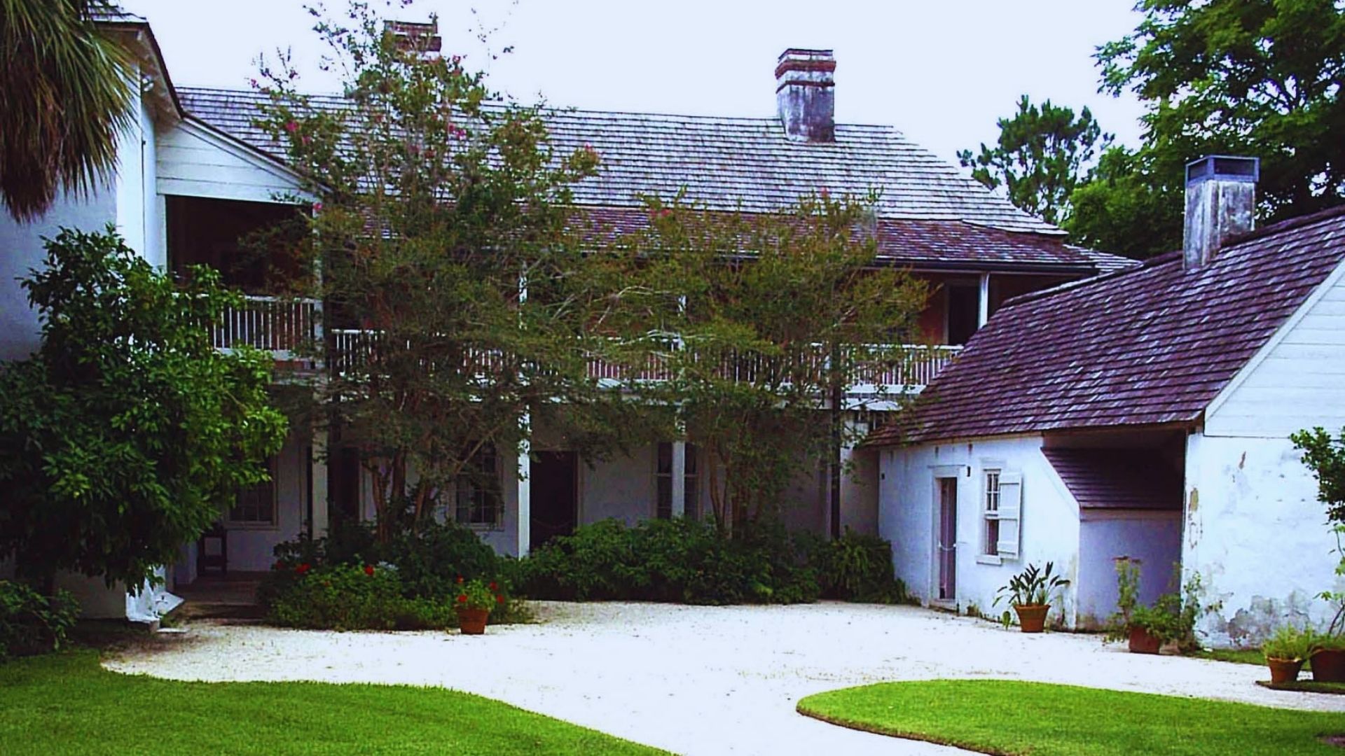 A white house featuring a driveway and a well-maintained garden in front.