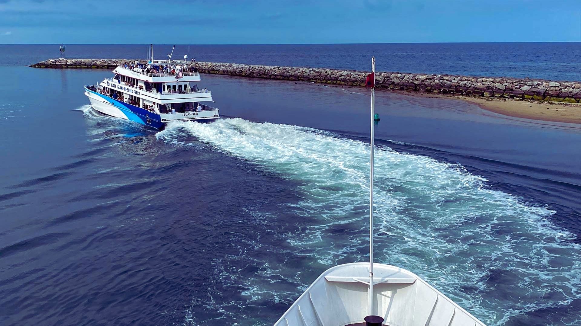 A boat gliding across calm water under a clear blue sky.