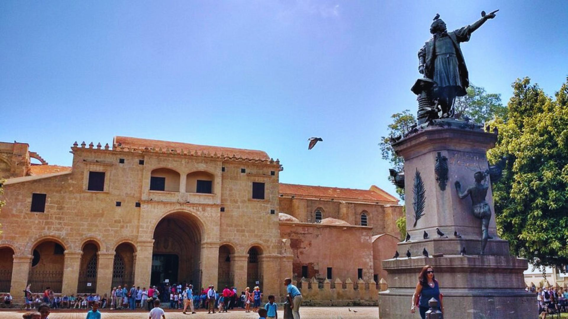 A statue of a man stands prominently in front of a historic building, showcasing intricate details and craftsmanship.