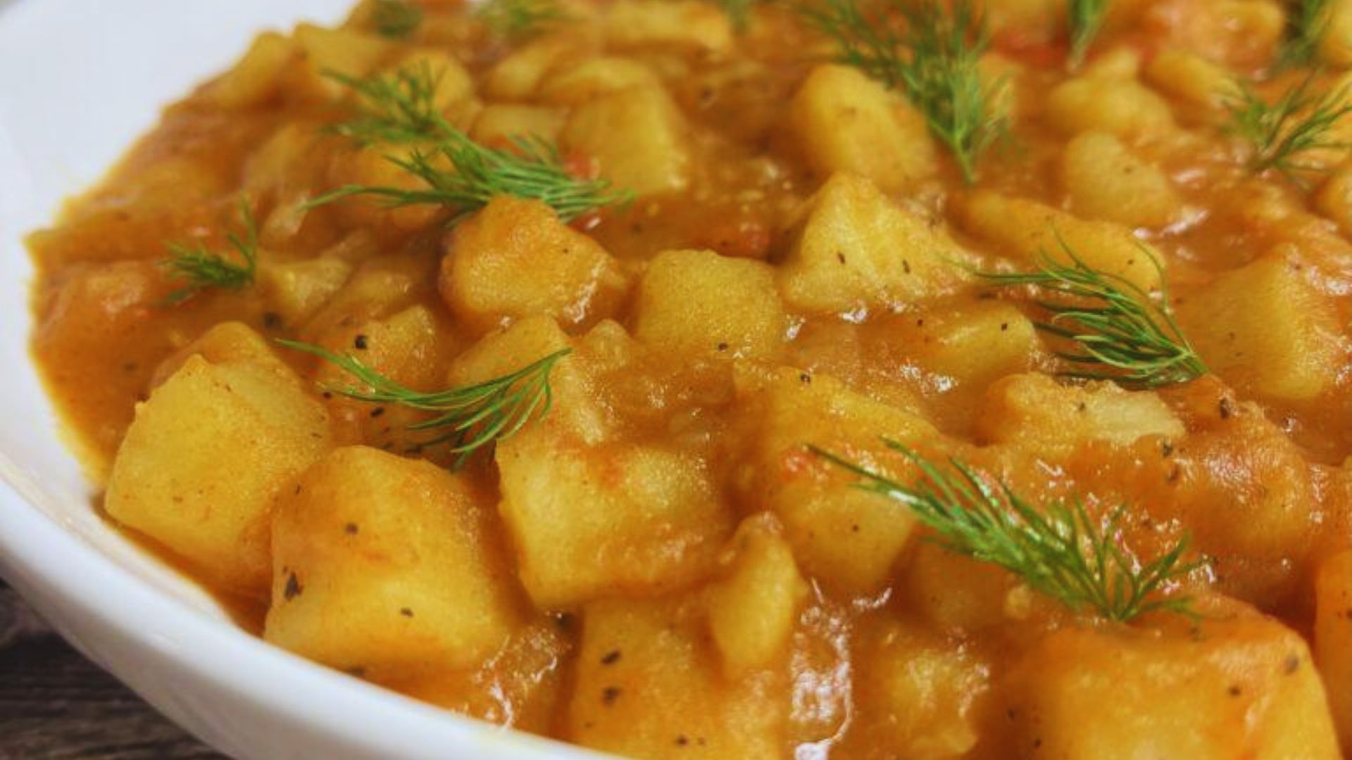 A bowl filled with potatoes and carrots, garnished with a fresh sprig of dill.
