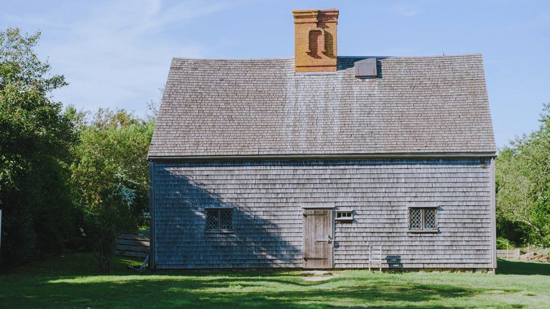 A cozy small house with a prominent chimney on the roof, nestled in a peaceful setting.