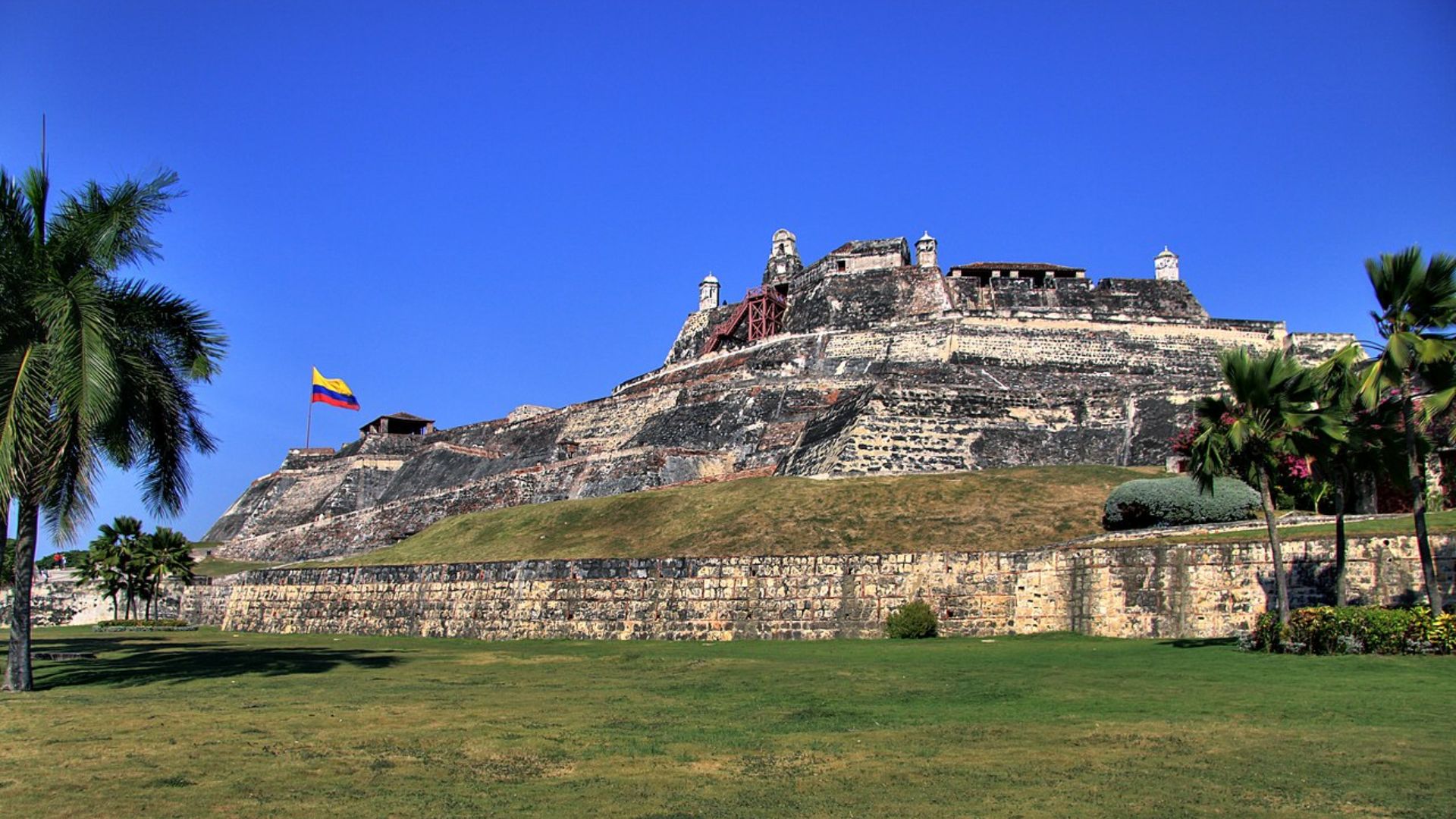 A large castle stands majestically with a flag waving in the background against a clear sky.