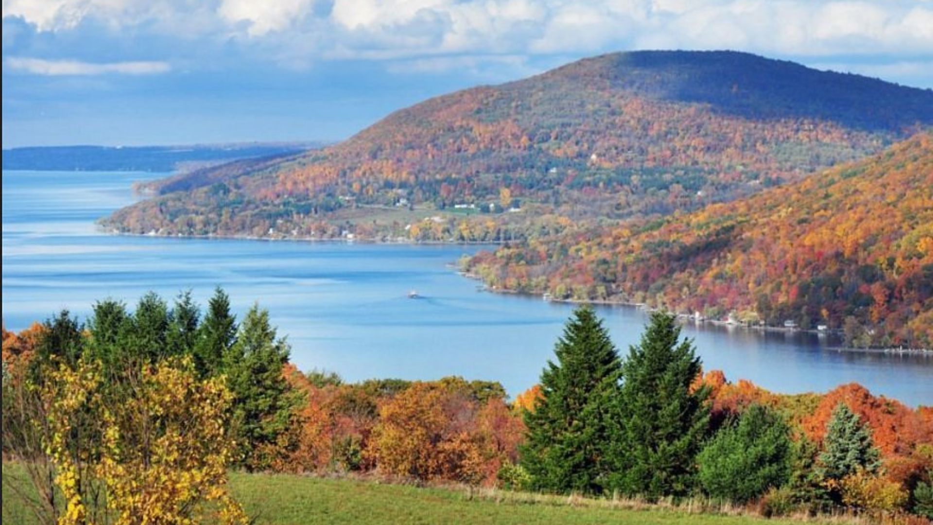 . A picturesque view of a lake surrounded by colorful fall foliage and majestic mountains in the background.