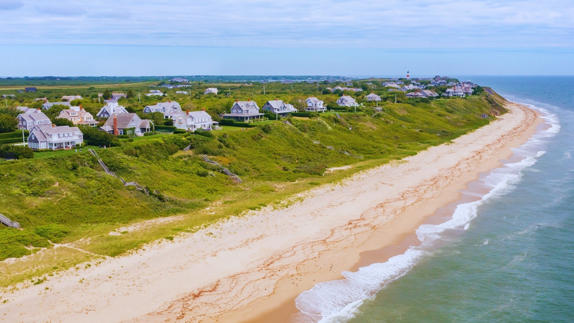 Aerial view of a beach with golden sand and houses lining the shore, showcasing the coastal landscape.