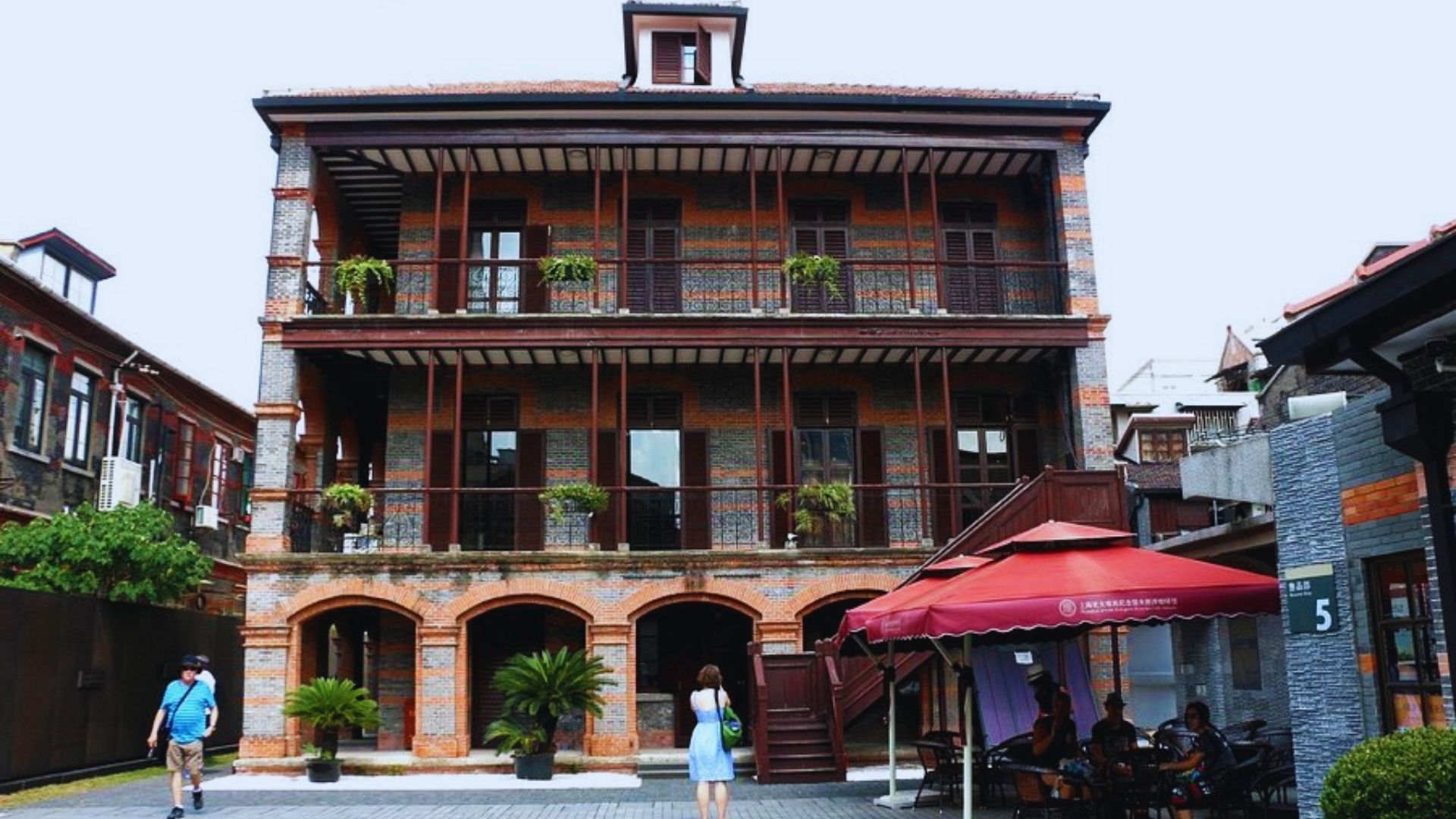 A building featuring a red umbrella on the balcony, providing shade and a pop of color against the structure.
