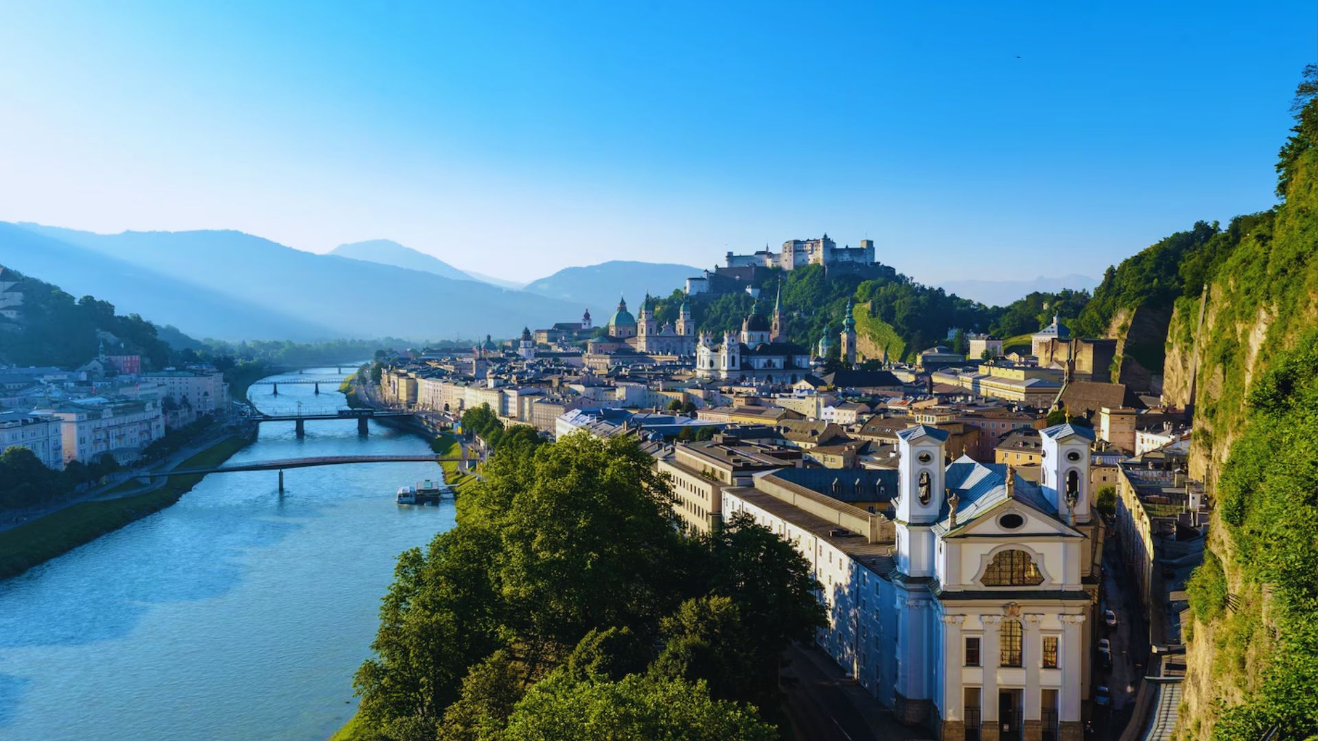 Scenic view of Salzburg, Austria, featuring the river and mountains in the background.
