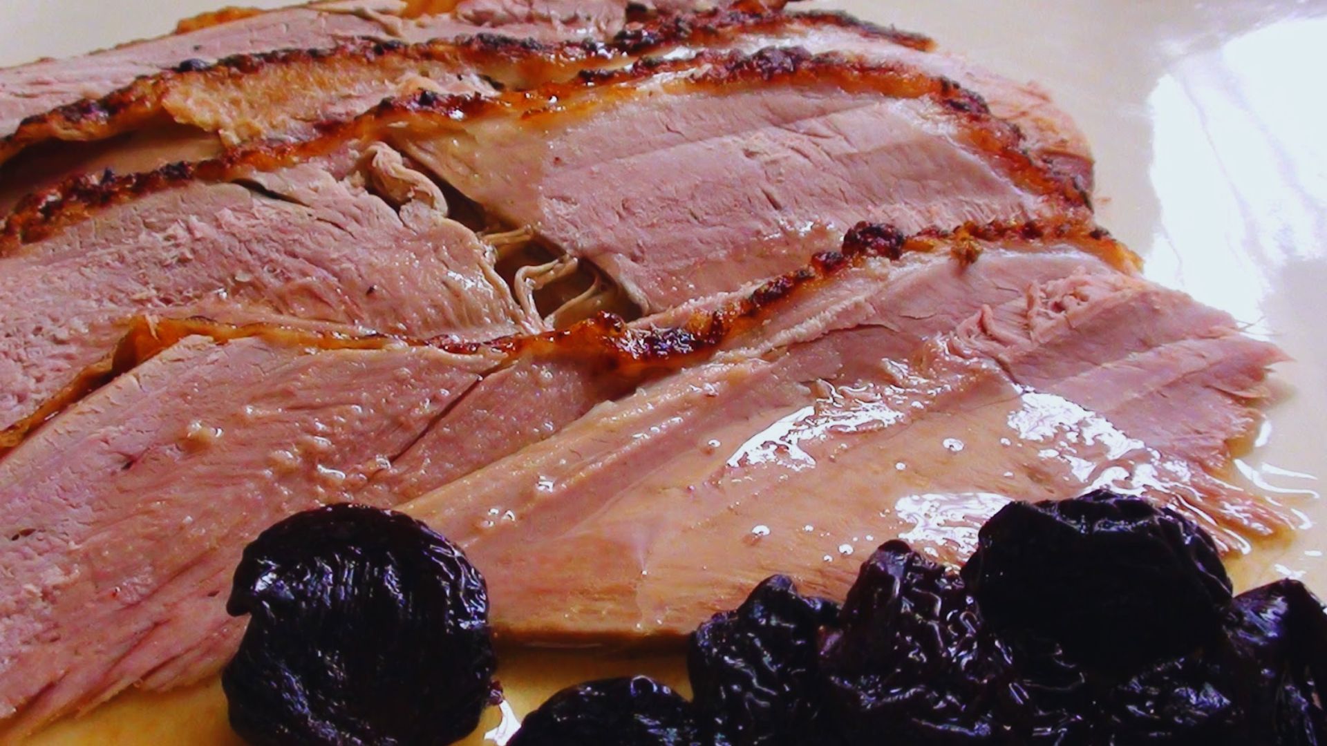 A plate featuring neatly sliced ham garnished with plump raisins.