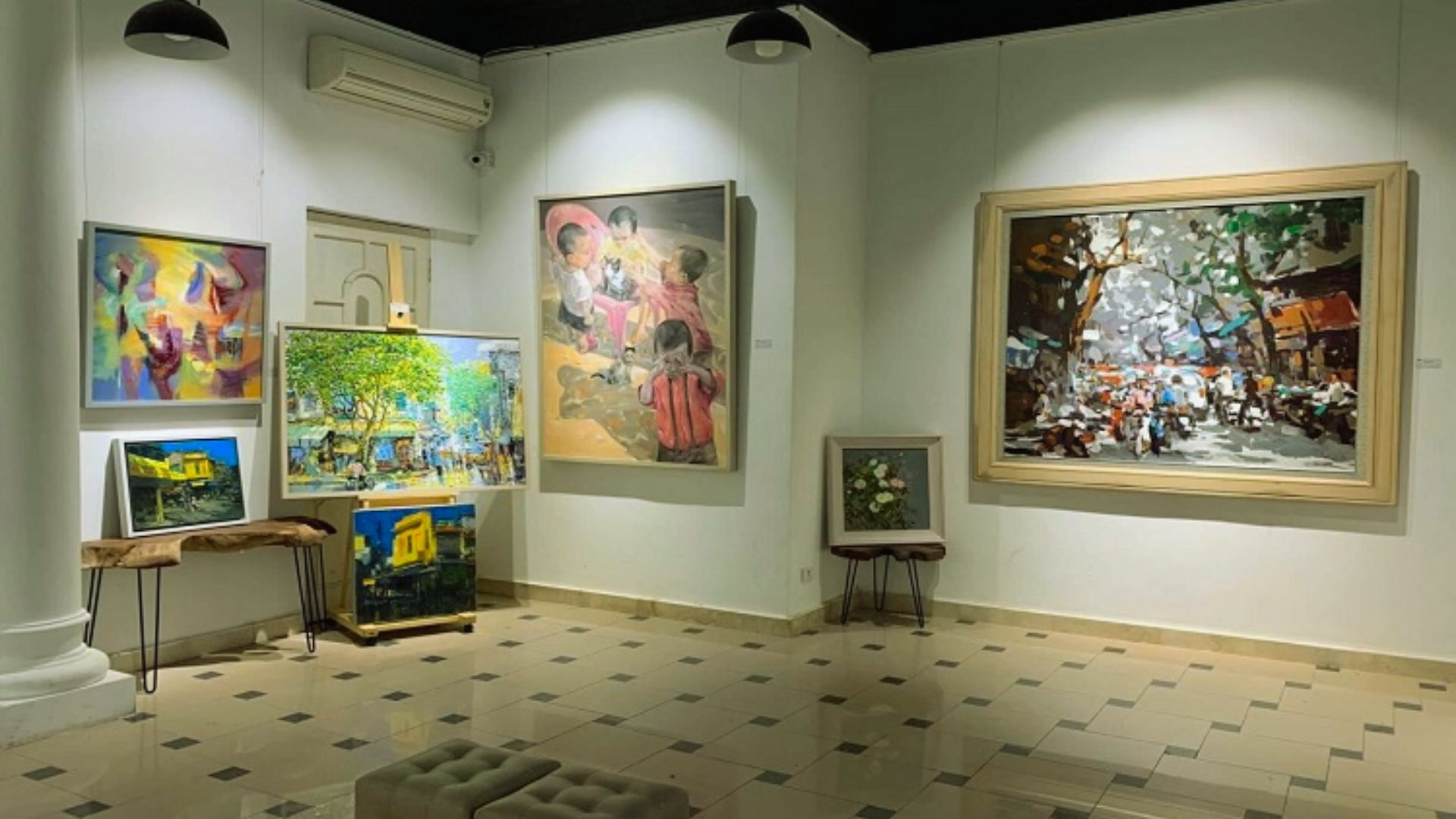 Art gallery interior displaying diverse paintings on a light-colored wall. Vibrant abstract, nature, and street scenes convey creativity and tranquility.