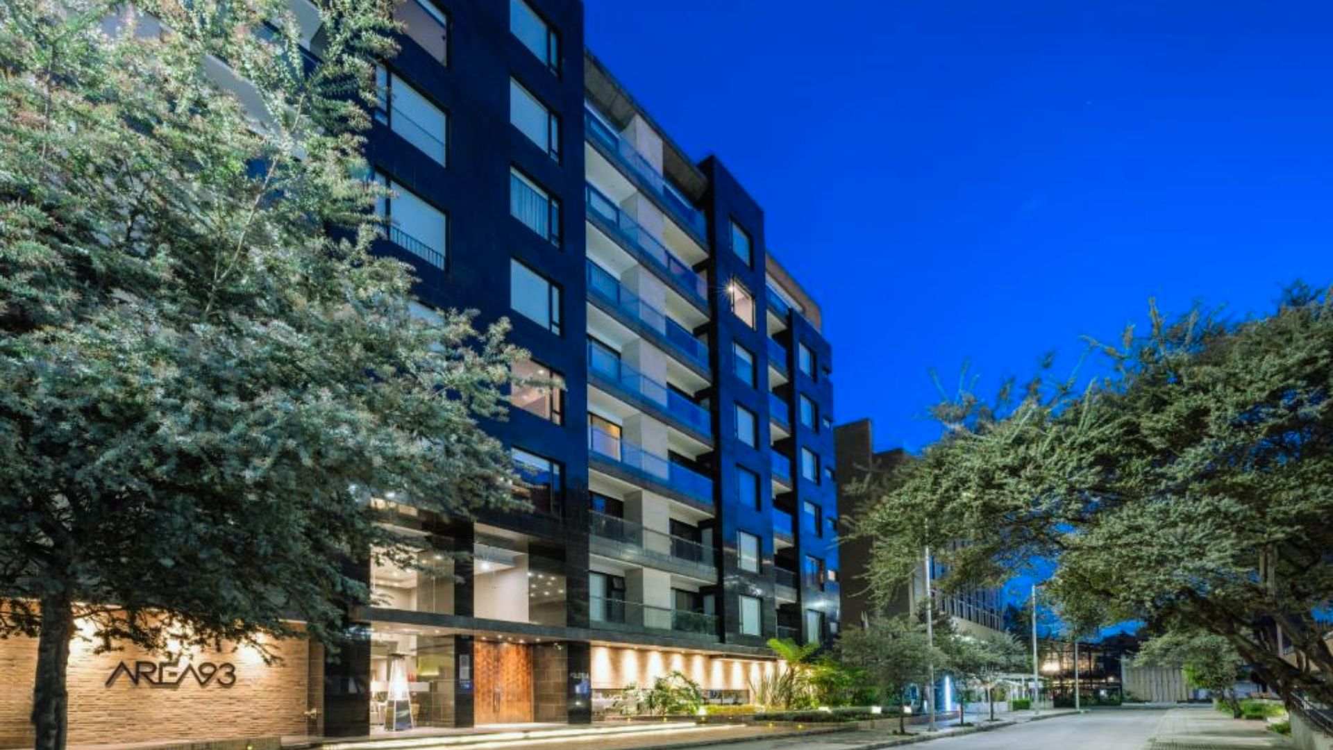 Exterior view of an apartment building illuminated at night, showcasing windows and architectural details against a dark sky.