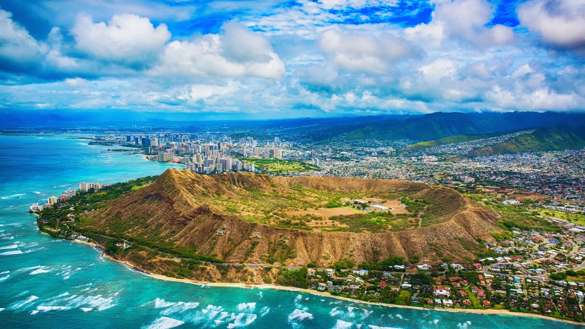 A scenic view of Diamond Head, a volcanic crater in Honolulu, Hawaii, showcasing its iconic shape against a clear blue sky.