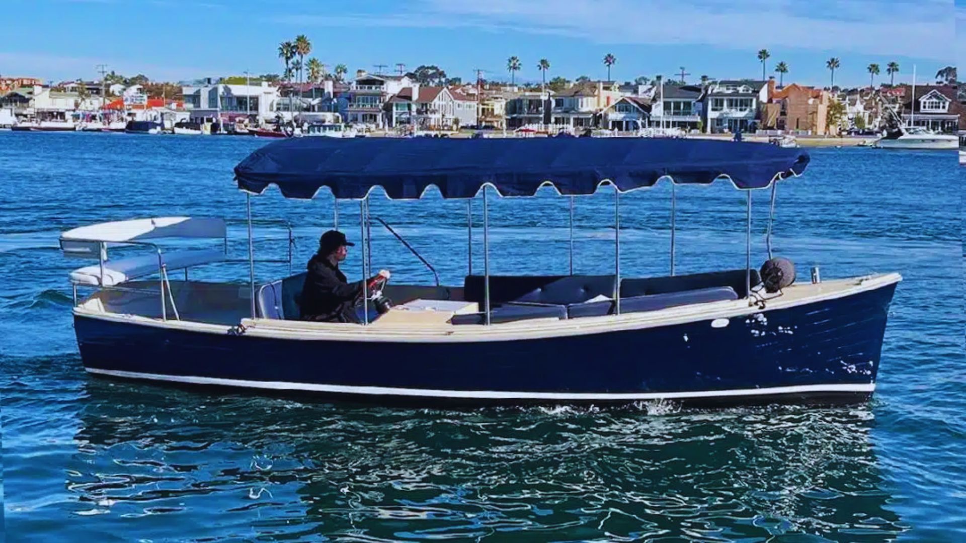 A man sits in the back of a boat, gazing out at the water with a calm expression.