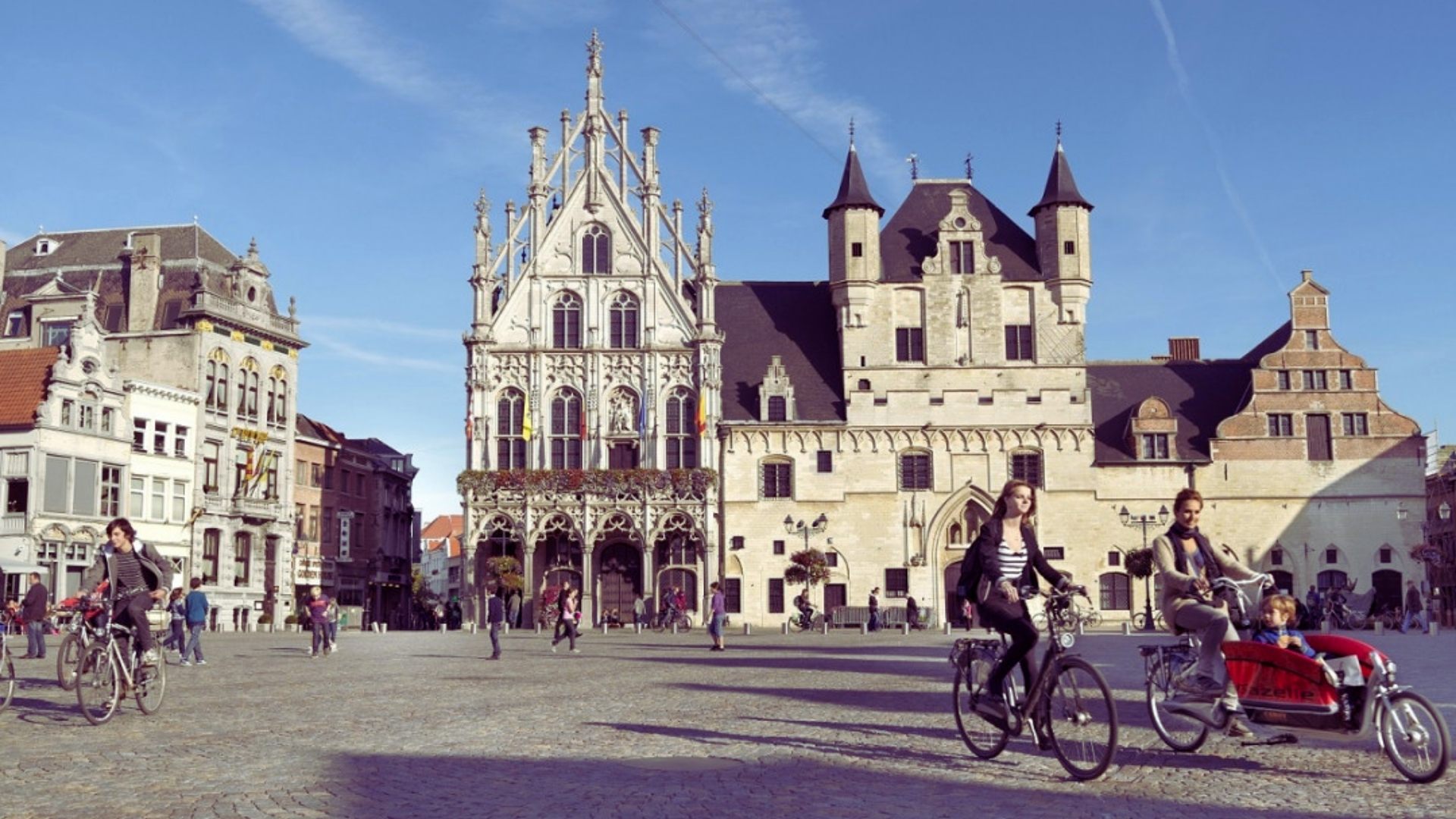 Cyclists pass by a prominent building, showcasing urban activity and transportation.