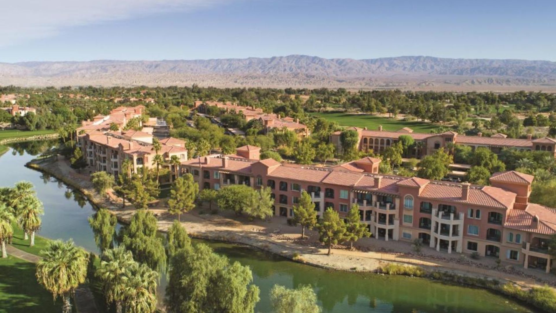 A resort nestled among lush palm trees with majestic mountains in the background, creating a serene tropical atmosphere.