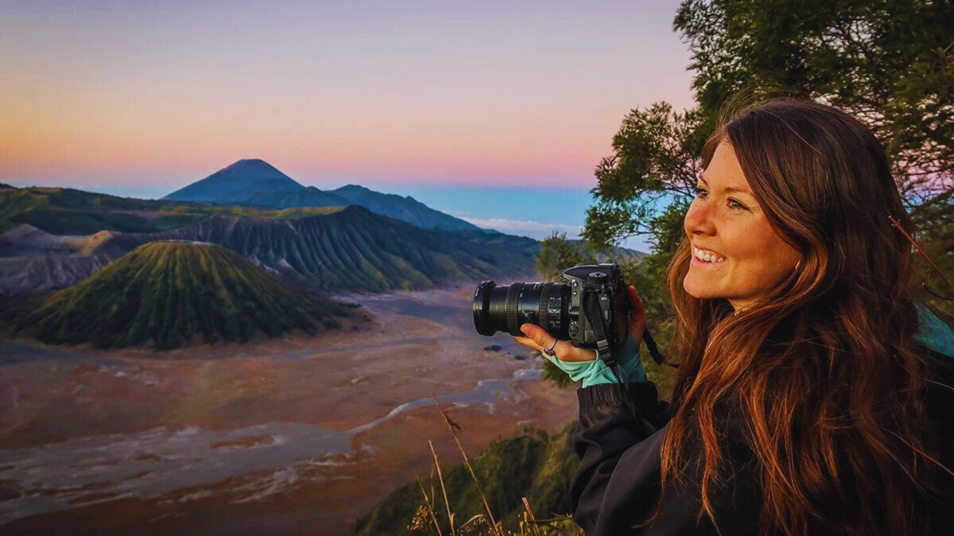 A woman photographing mountains during a vibrant sunset, capturing the beauty of nature's colors.
