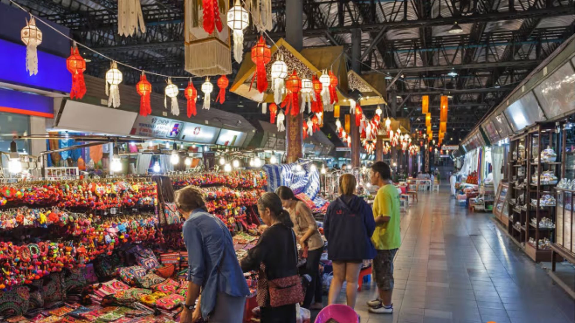 People shopping in a vibrant Asian market illuminated by colorful lights, creating a lively and festive atmosphere.