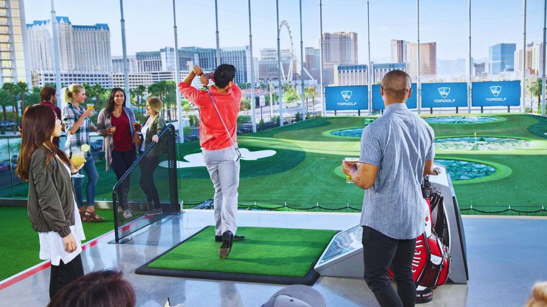 A group of people enjoying a golf simulator, focused on their swings and the virtual course displayed on the screen.