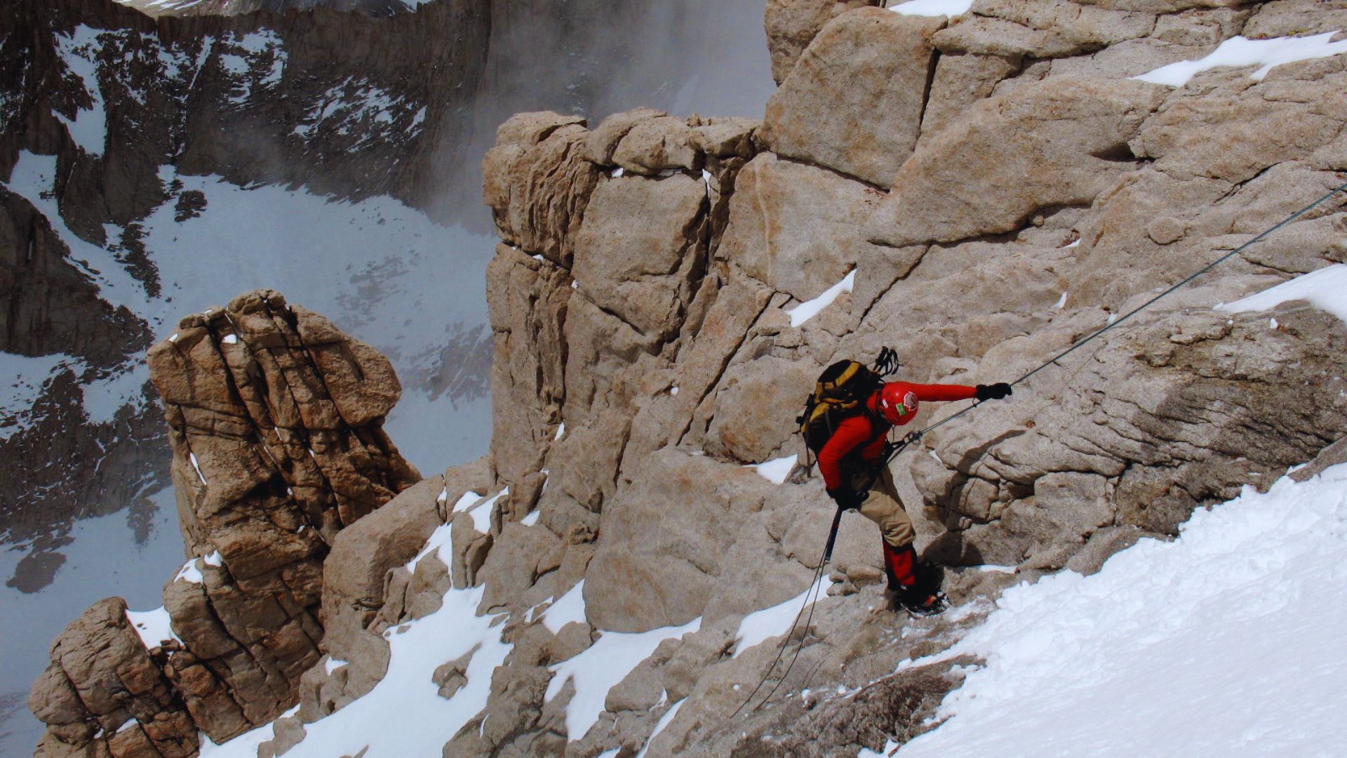 A man ascending a mountain, demonstrating perseverance amidst rocky terrain and a clear blue sky.