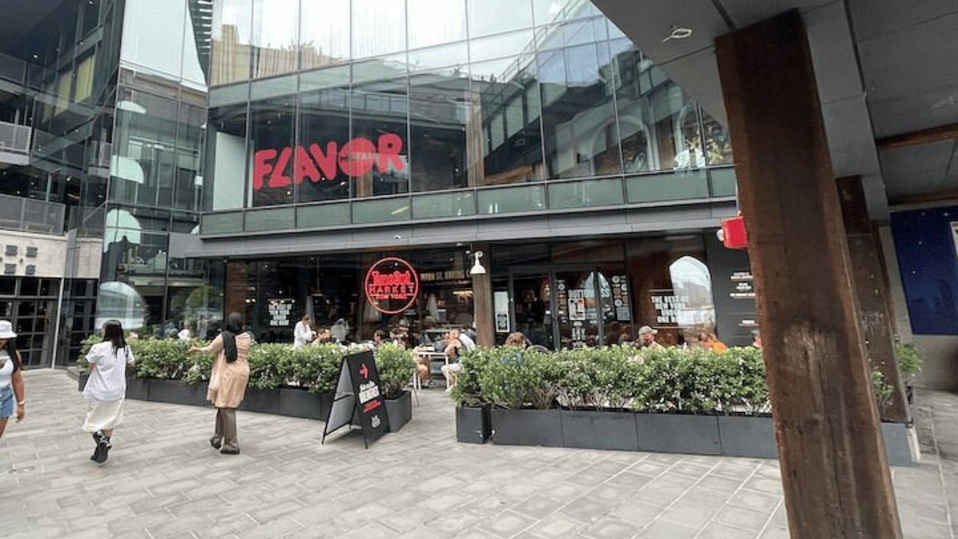 People walking outside a restaurant, enjoying the atmosphere and socializing in a lively outdoor setting.
