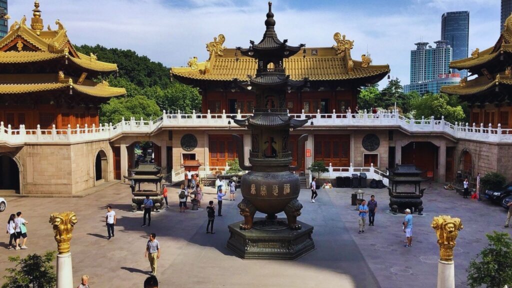 A large Chinese temple surrounded by a fountain in the center, showcasing intricate architectural details and vibrant colors.