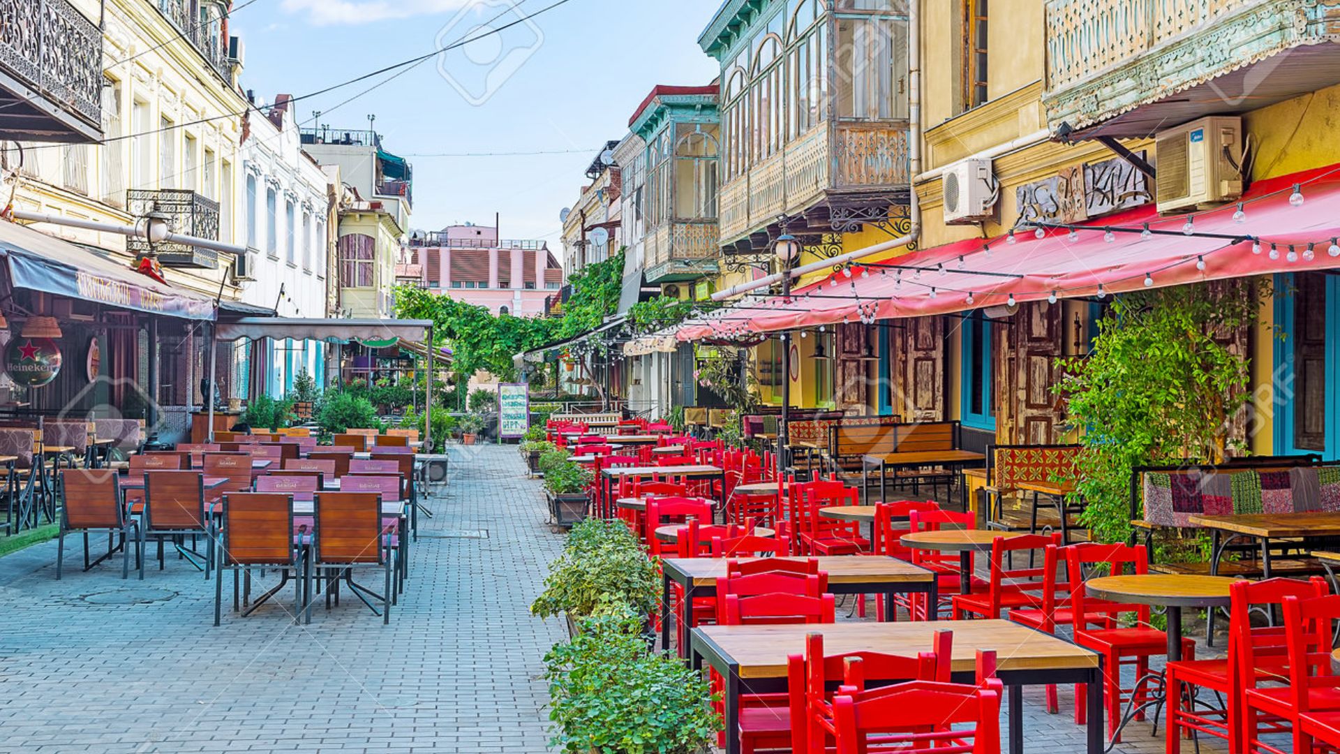 A street scene featuring tables and chairs set up outside a building, inviting outdoor dining and socializing.