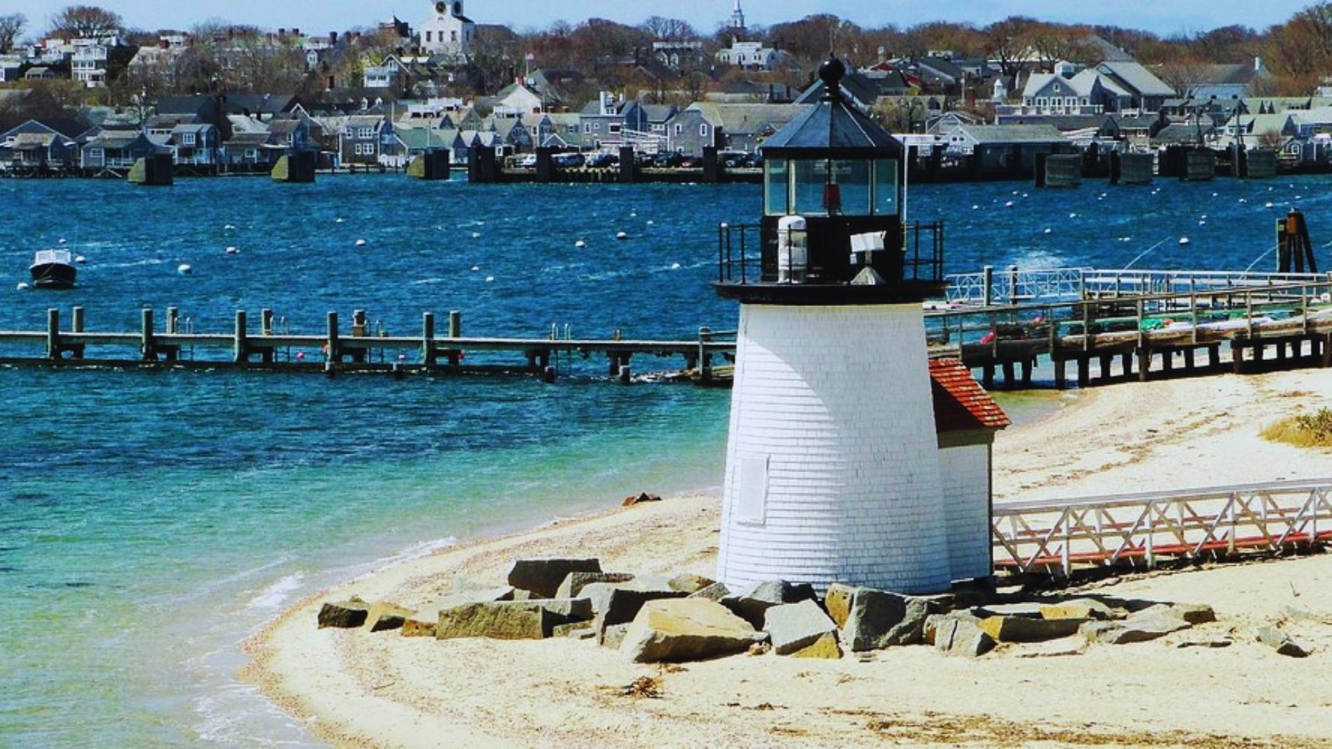 A lighthouse stands tall on the beach, overlooking the shore and guiding ships with its light.