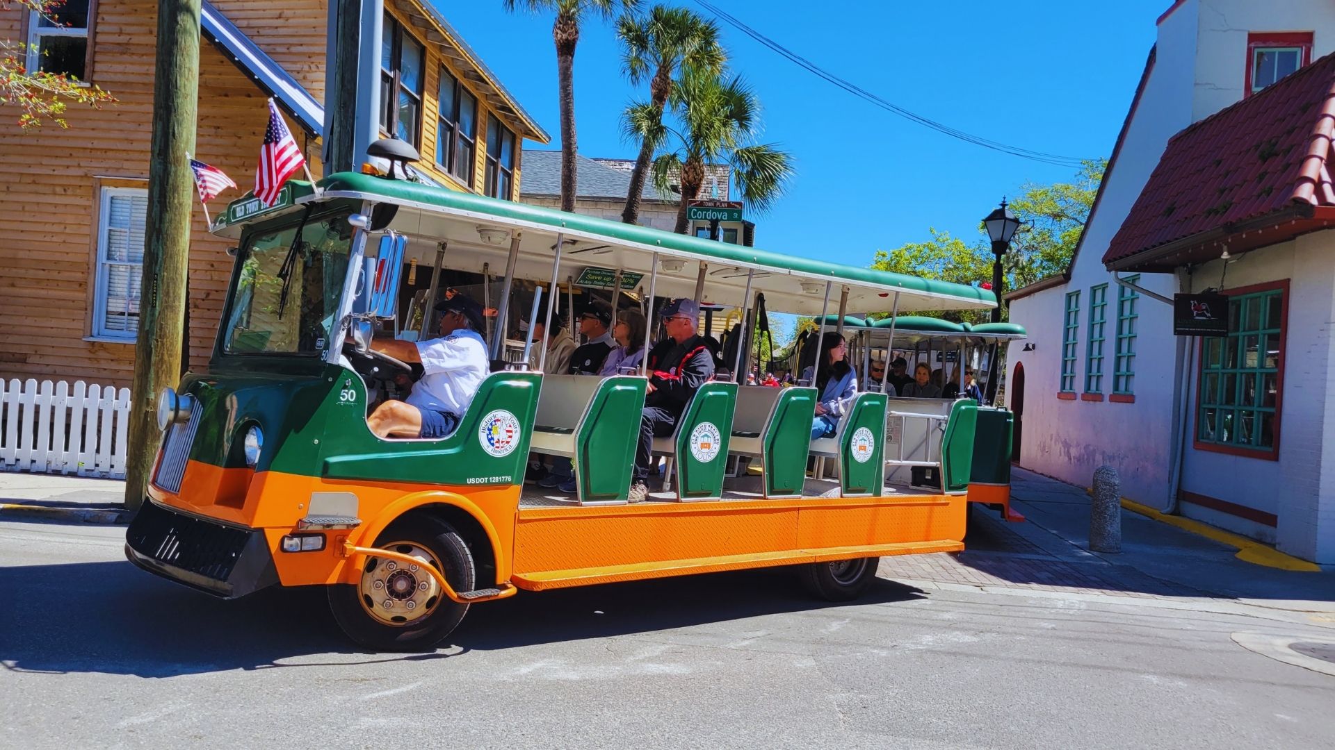 A trolley car travels down a street, with passengers visible through the windows, enjoying the ride.