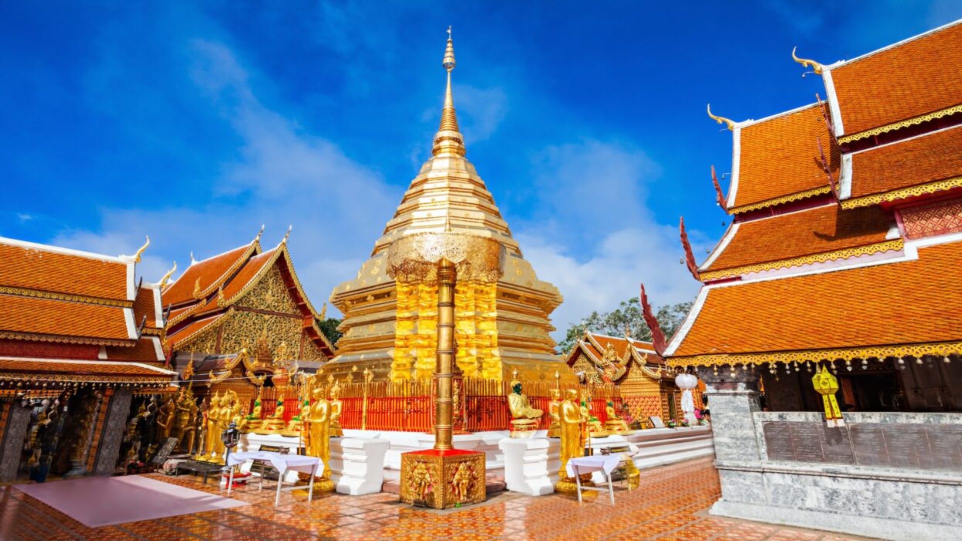 Golden Wat Phra That temple in Thailand, featuring intricate architecture and a shimmering golden stupa against a blue sky.