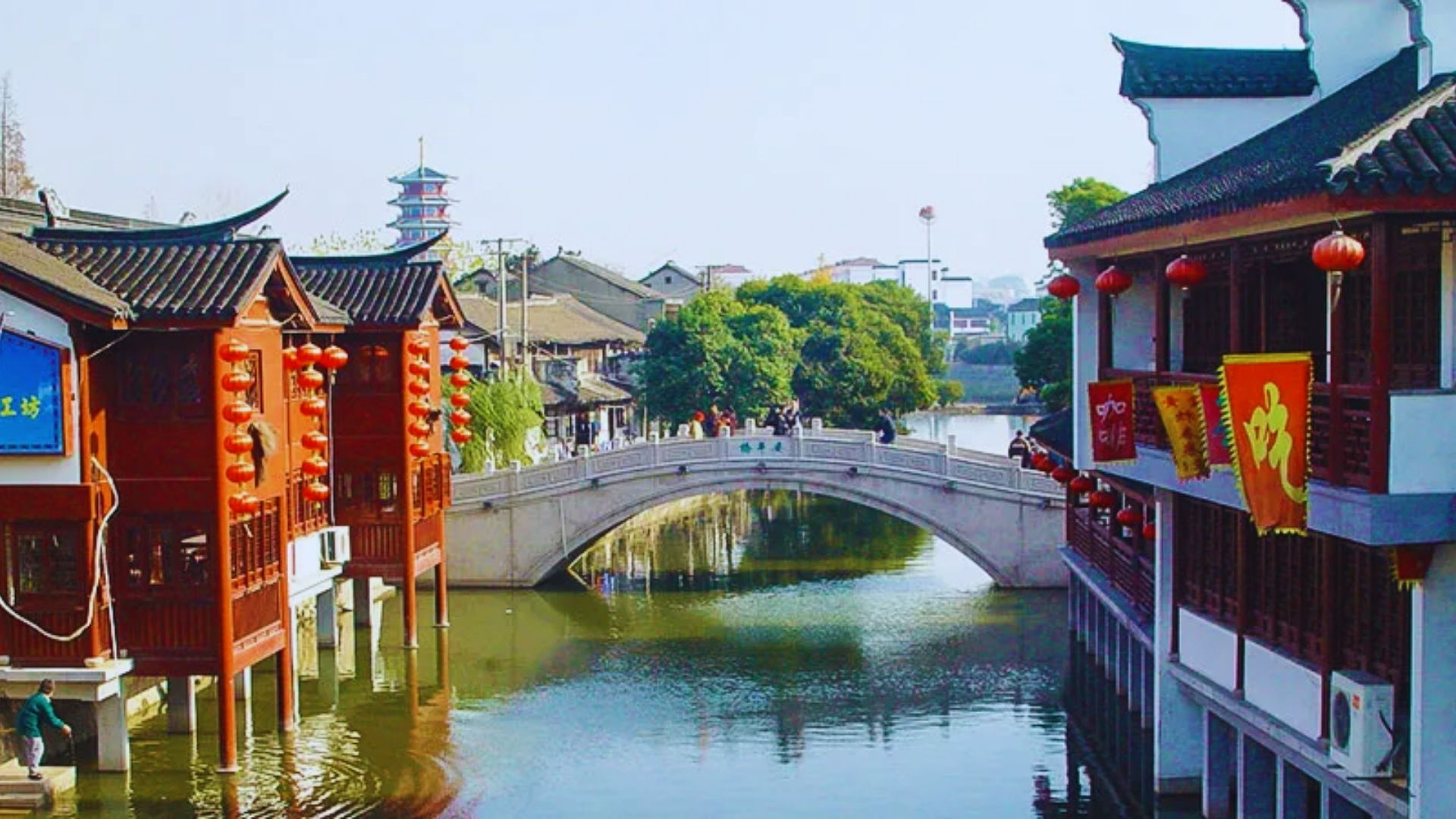 A scenic canal in an oriental city, featuring traditional buildings and elegant bridges spanning the waterway.