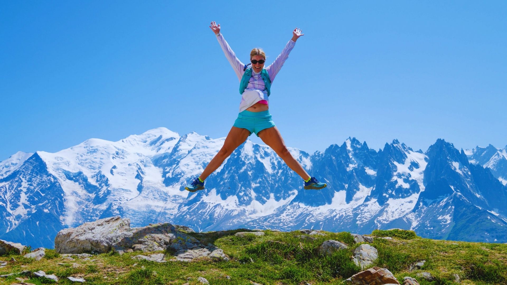 A woman joyfully jumping in the air with her arms outstretched, expressing excitement and freedom.