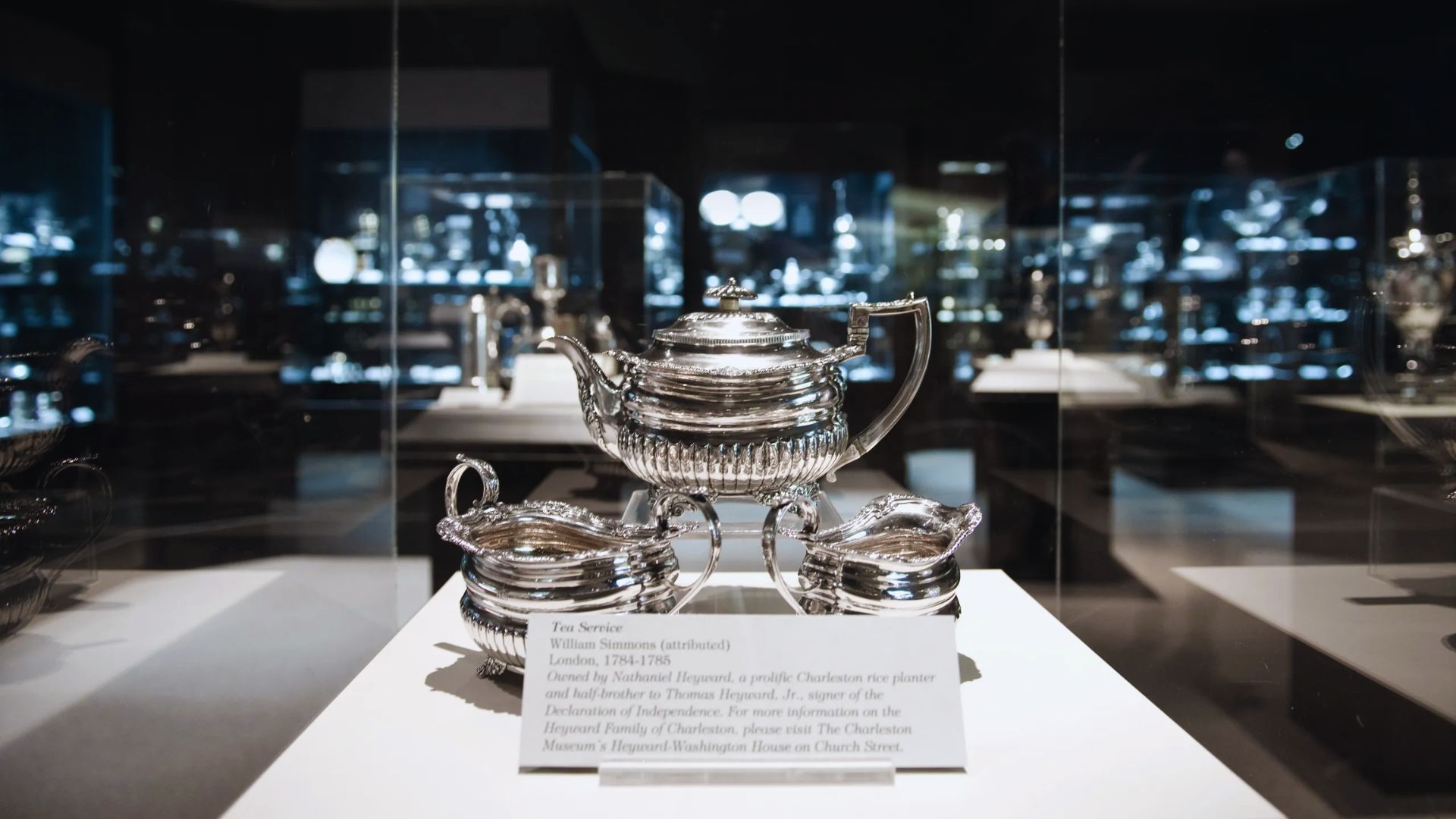 A silver tea set elegantly displayed in a museum, showcasing intricate designs and craftsmanship.