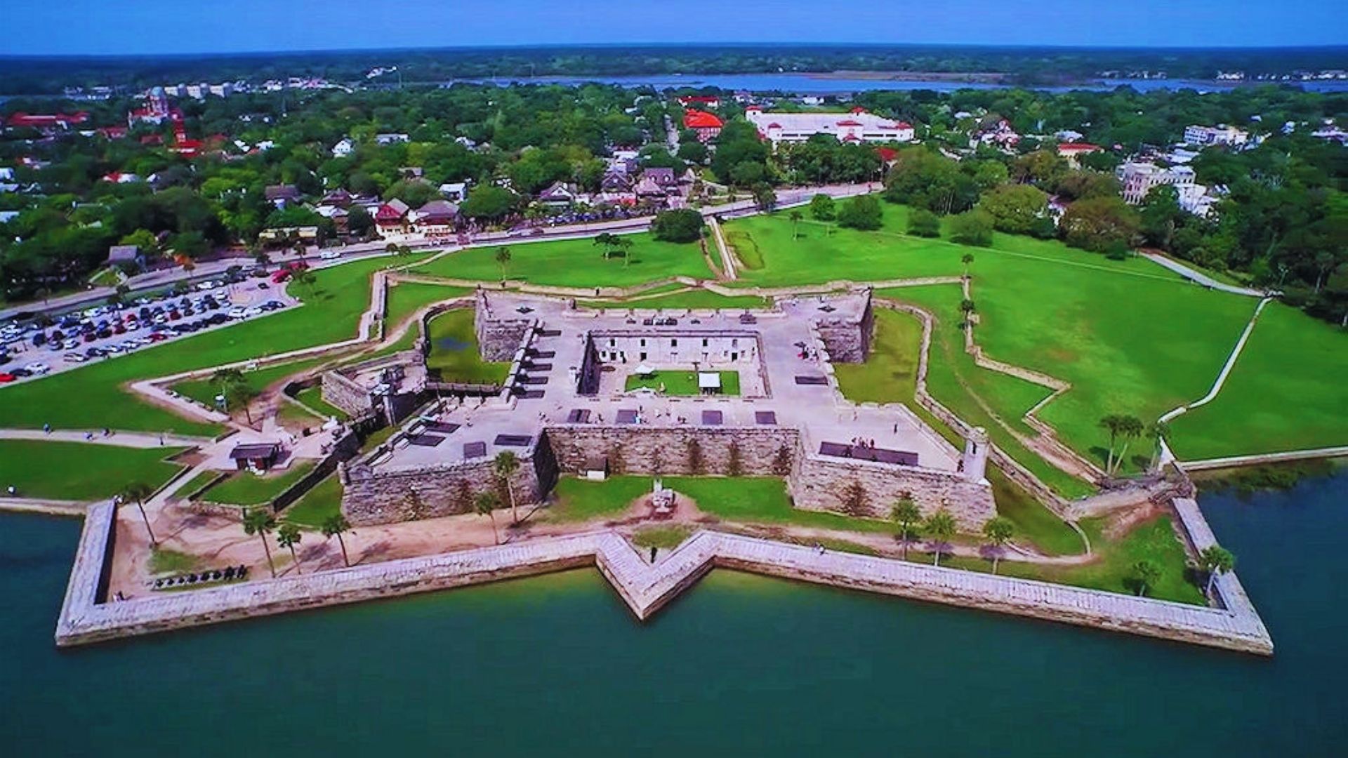 Aerial view of a majestic castle surrounded by water, showcasing its towers and reflection in the serene lake below.