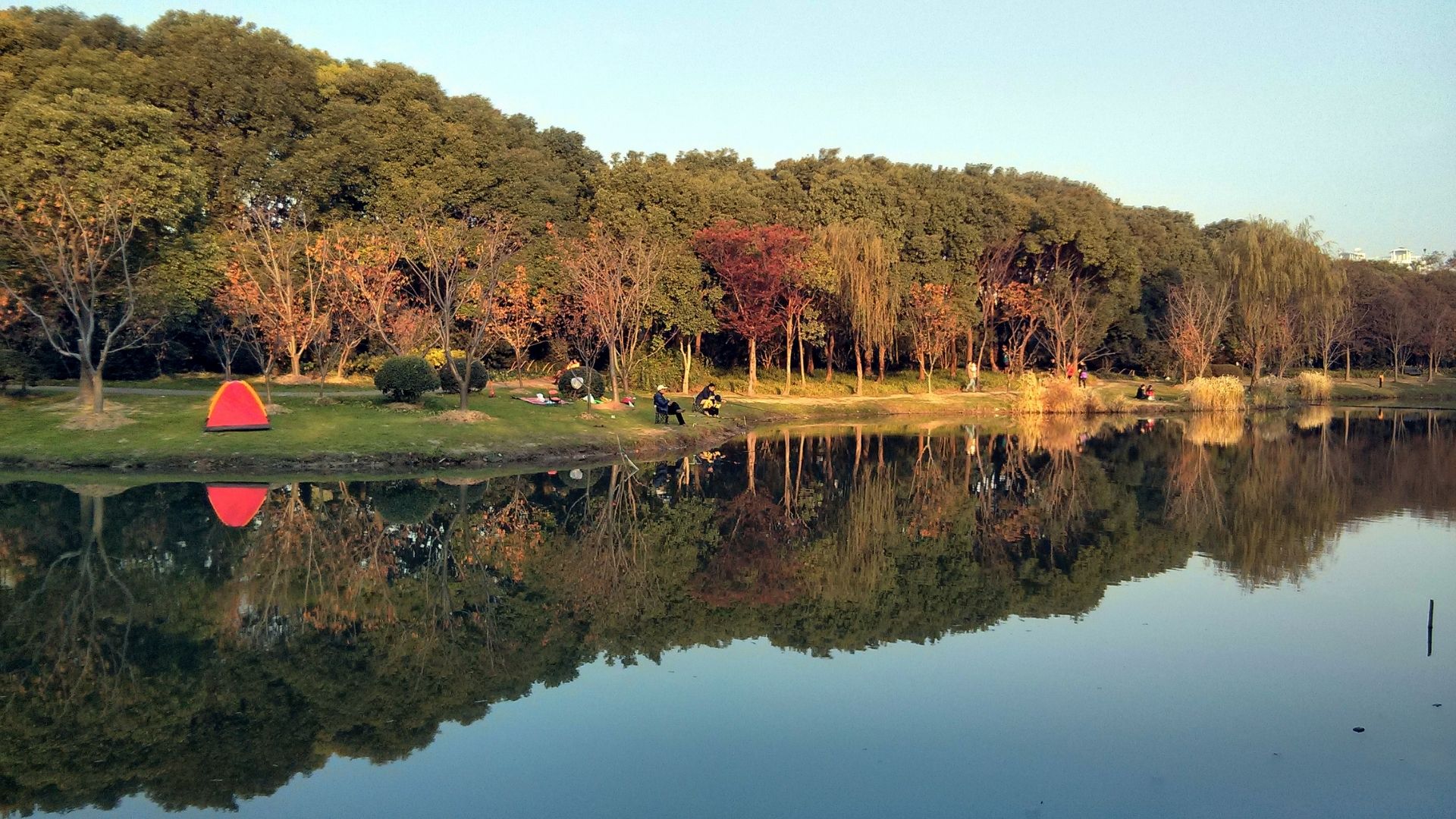 A red umbrella is reflected in calm water, creating a vibrant contrast against the surface.