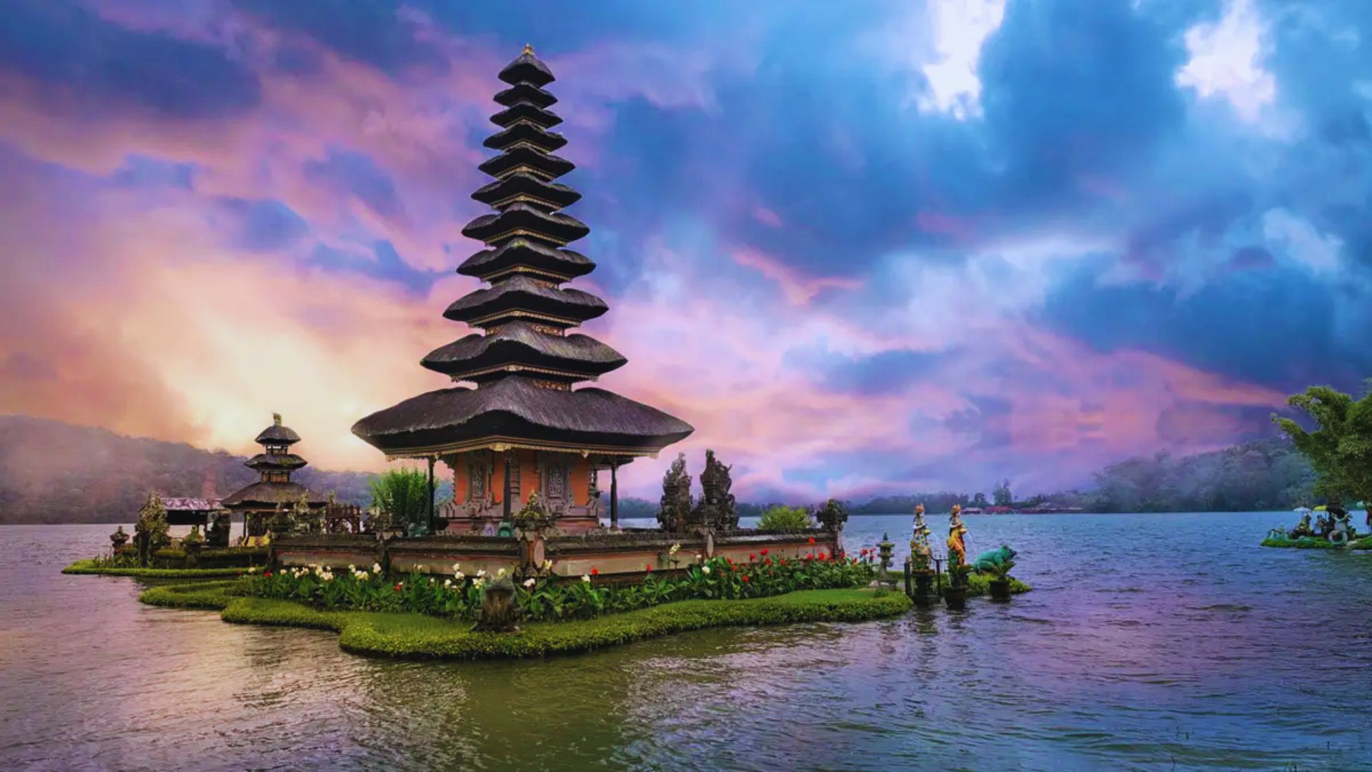 A serene temple with a multi-tiered roof sits on a small, lush island in a lake. The sky is vibrant with pink and purple hues, creating a tranquil scene.