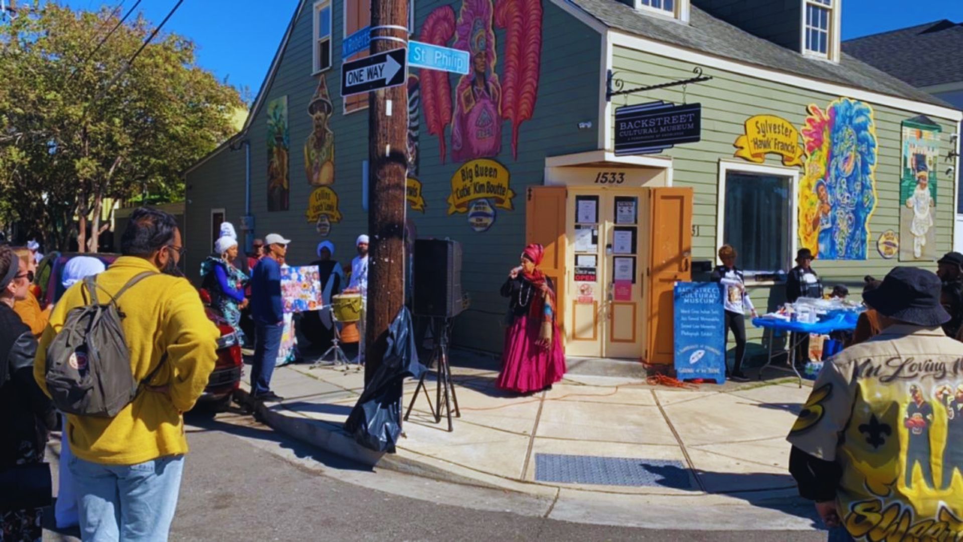 Several people are positioned outside a building that displays an artistic mural on its exterior.