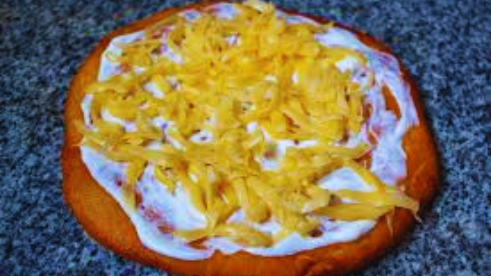 A pizza topped with melted cheese and a dollop of sour cream, showcasing a creamy and savory combination.