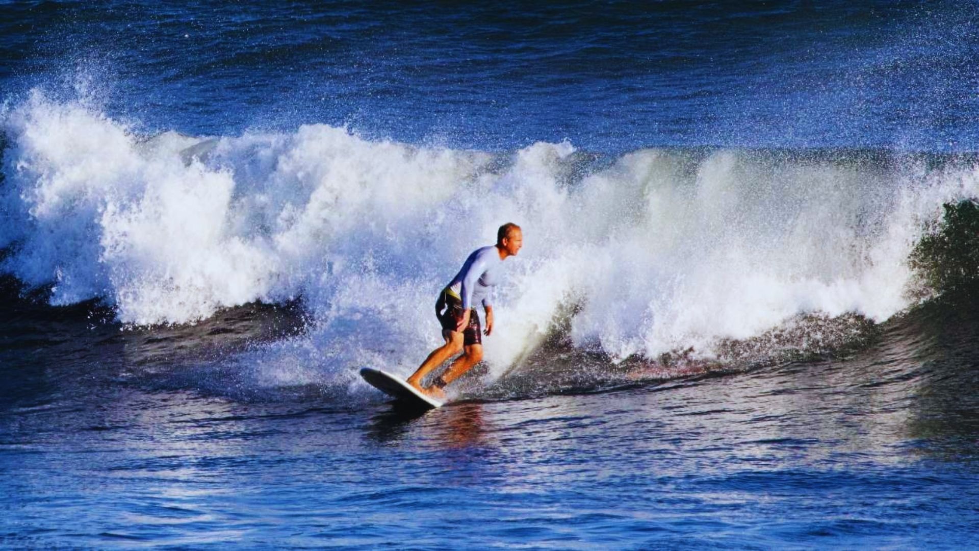 A man skillfully rides a wave on a surfboard, showcasing his balance and agility in the ocean.