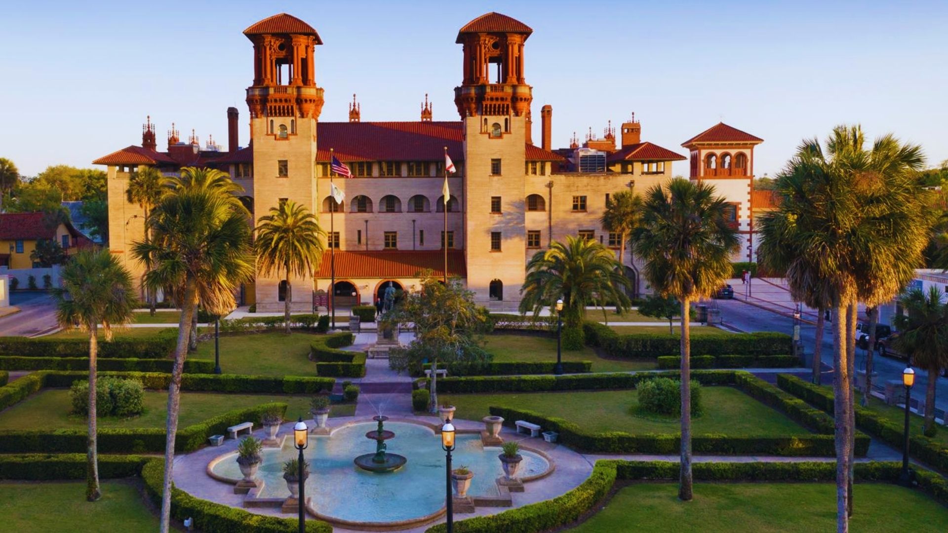 A large building featuring two towers and a central fountain in front, set against a clear blue sky.