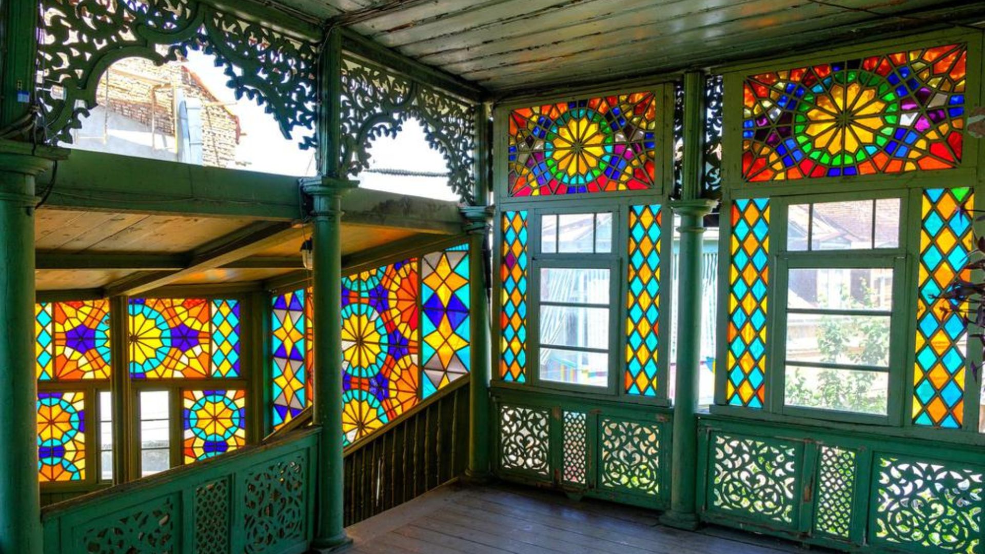 Colorful stained glass windows illuminate a house, showcasing intricate designs and vibrant hues.