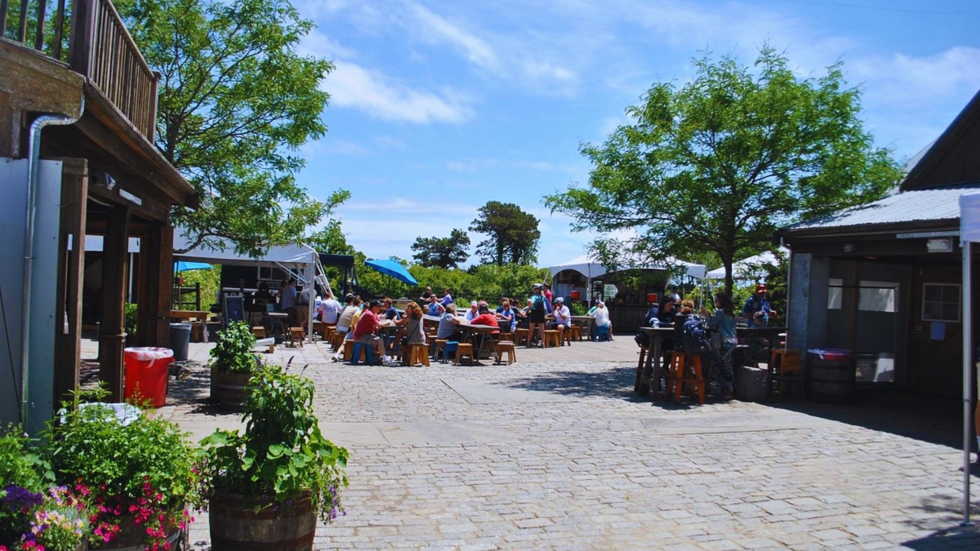 Outdoor courtyard scene with tables and chairs set up along a street for dining.