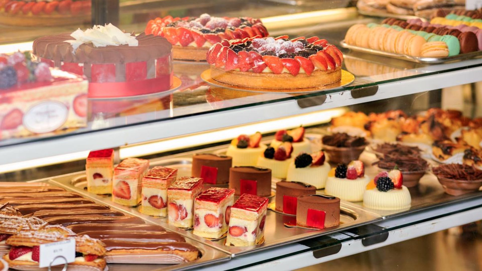 A display case showcasing an assortment of colorful pastries, including cakes, tarts, and cookies.