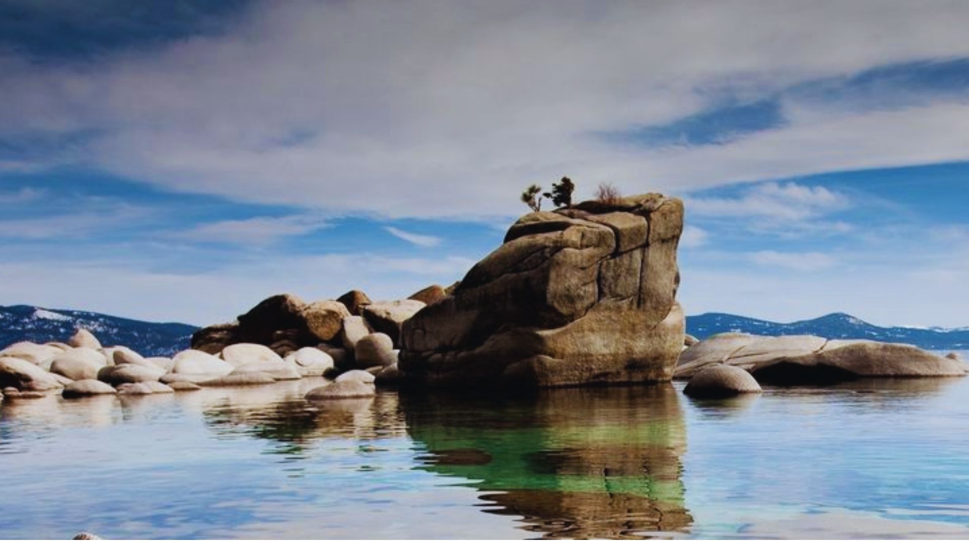 A couple stands on a rock in the water, enjoying the serene surroundings and each other's company.