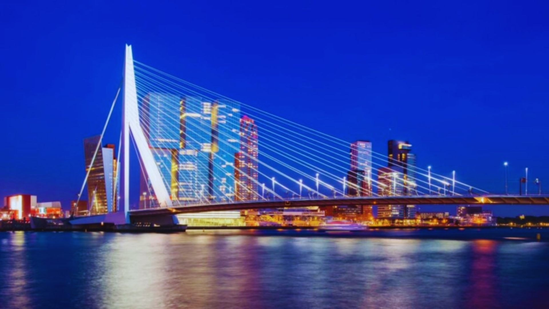 City skyline illuminated at night with a bridge prominently featured in the foreground.